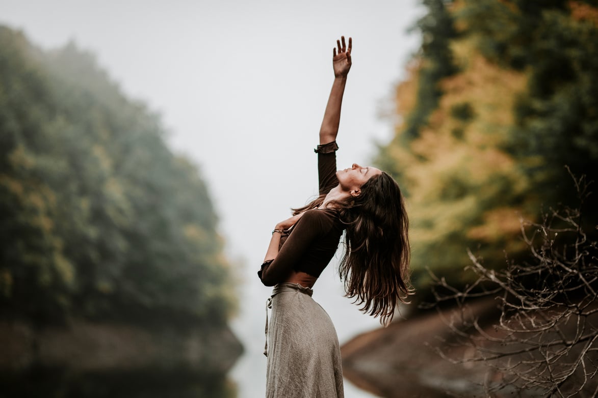 Woman with One Hand on Chest and Other Reaching to Sky